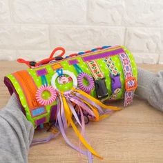 a child's hand is holding a colorful purse