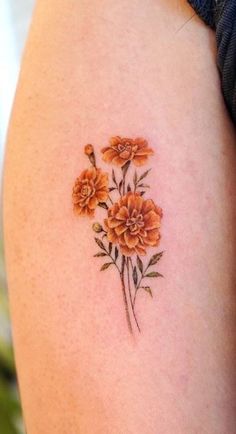 an orange flower tattoo on the right side of the thigh, with three flowers in it