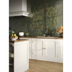 a kitchen with white cabinets and green tile backsplash