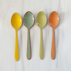 four spoons lined up next to each other on a white counter top with different colors