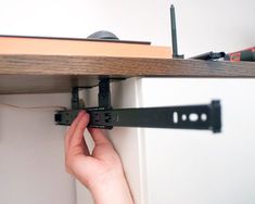 a person is working on a shelf with a pair of black straps attached to it