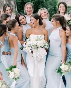 a group of women standing next to each other holding bouquets and smiling at the camera