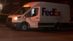 a fed ex delivery truck parked in front of a building at night with its lights on