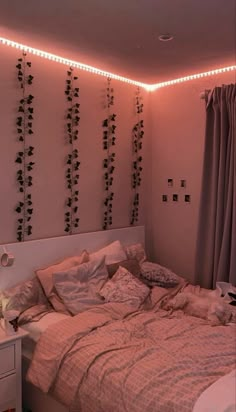 an unmade bed in a room with lights on the wall