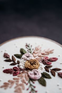 a close up of a embroidery on a wooden hoop with flowers and leaves painted on it