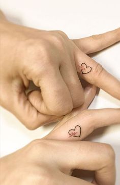 two hands with heart tattoos on their fingers