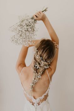 the back of a woman's head wearing a wedding dress and holding flowers in her hair