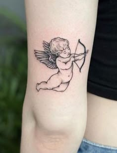 a small cupid tattoo on the left arm with an arrow and bow in it