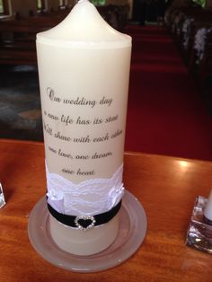 a white candle with a poem on it sitting on a table next to some candles