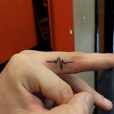 a person's finger with a heartbeat tattoo on it