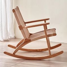 a wooden rocking chair sitting on top of a hard wood floor next to a window