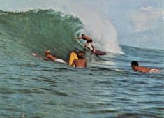 three surfers are riding the waves on their surfboards in the ocean while another man watches