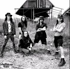 five people posing for a photo in front of an old barn