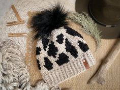 a knitted hat with black and white designs on it next to some knitting needles