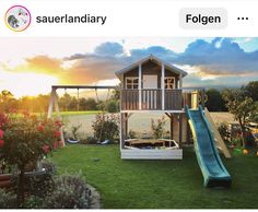 a small wooden house with a slide in the grass and flowers around it, on an instagram page