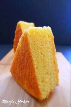 two pieces of yellow cake sitting on top of a wooden cutting board