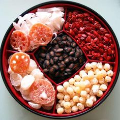 an assortment of fruits and nuts in a red bowl