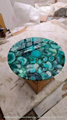 a glass plate sitting on top of a wooden box covered in blue and green marble