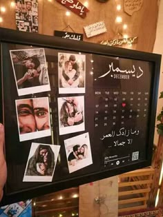 a person holding up a framed calendar with pictures on it