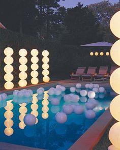 an outdoor pool is lit up with lights and balloons for the party guests to enjoy