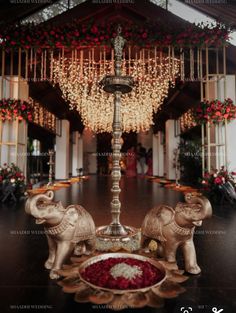 an elephant statue sitting on top of a wooden table next to a vase filled with flowers