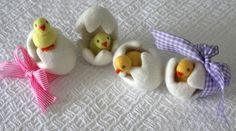 three small stuffed animals sitting next to each other on a white surface with pink ribbon