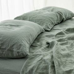 an unmade bed with green sheets and pillows