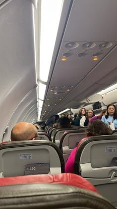 people sitting in seats on an airplane with their backs turned to the side as they take pictures