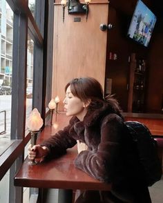 a woman sitting at a table looking out the window