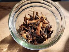 a glass bowl filled with cloves on top of a wooden table