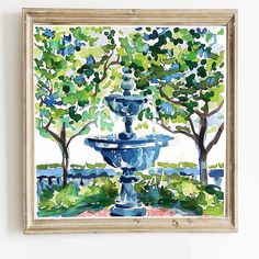 a water fountain in the middle of a park with trees and bushes around it, framed on a wall