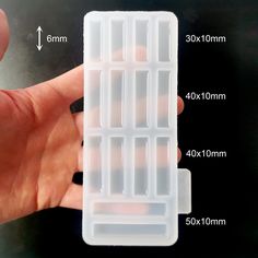 a hand holding an empty plastic container with measurements for the top and bottom compartments on it