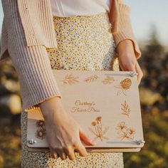 a woman holding a wooden box with flowers on it