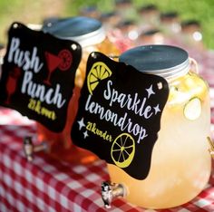 two mason jars filled with lemonade sit on a checkered tablecloth covered picnic table