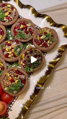 a white plate topped with crackers covered in toppings next to tomatoes and lettuce