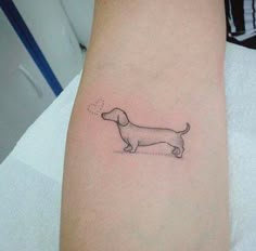 a small dachshund tattoo on the arm