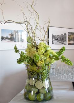 a vase filled with green and white flowers sitting on top of a table next to wine glasses