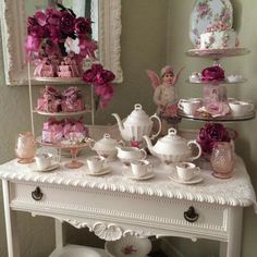 a white table topped with lots of tea cups and saucers covered in pink flowers