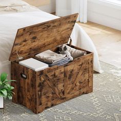 an open wooden box sitting on top of a bed next to a potted plant