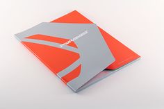 an orange and gray book on a white surface with the cover folded up to show it's logo