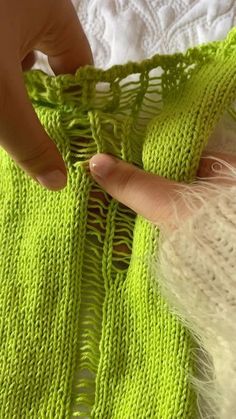 someone is crocheting the edge of a green sweater