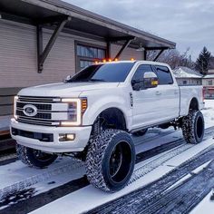 a white truck is parked in front of a house with snow on the ground around it