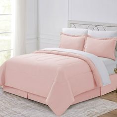 a bed with pink sheets and pillows in a room