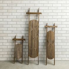 three pieces of wood sitting next to each other on top of a white brick wall