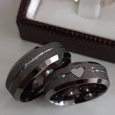 two wedding rings with hearts on them sitting next to a box