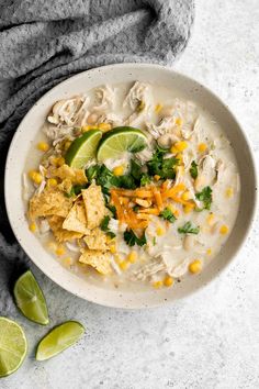 a white bowl filled with chicken tortilla soup and garnished with limes