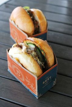 two sandwiches sitting on top of each other in small boxes with meat and vegetables inside