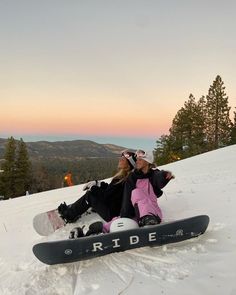 two people sitting in the snow on top of a mountain with their skis and snowboards