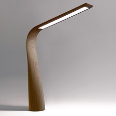 a wooden table lamp with a dim light on it's side and a white wall in the background