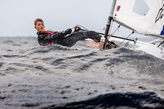 a man riding on top of a sailboat in the ocean